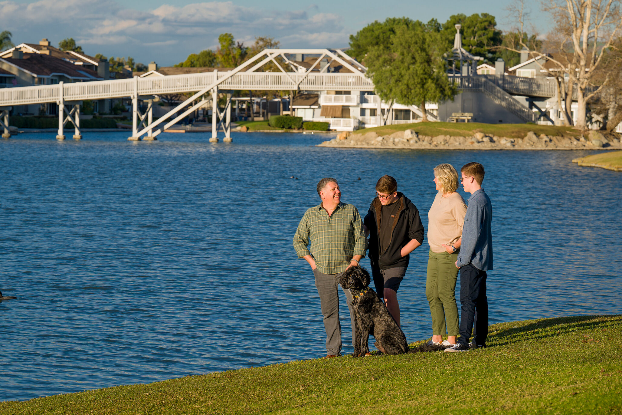 Four adults and a dog standing in front of water